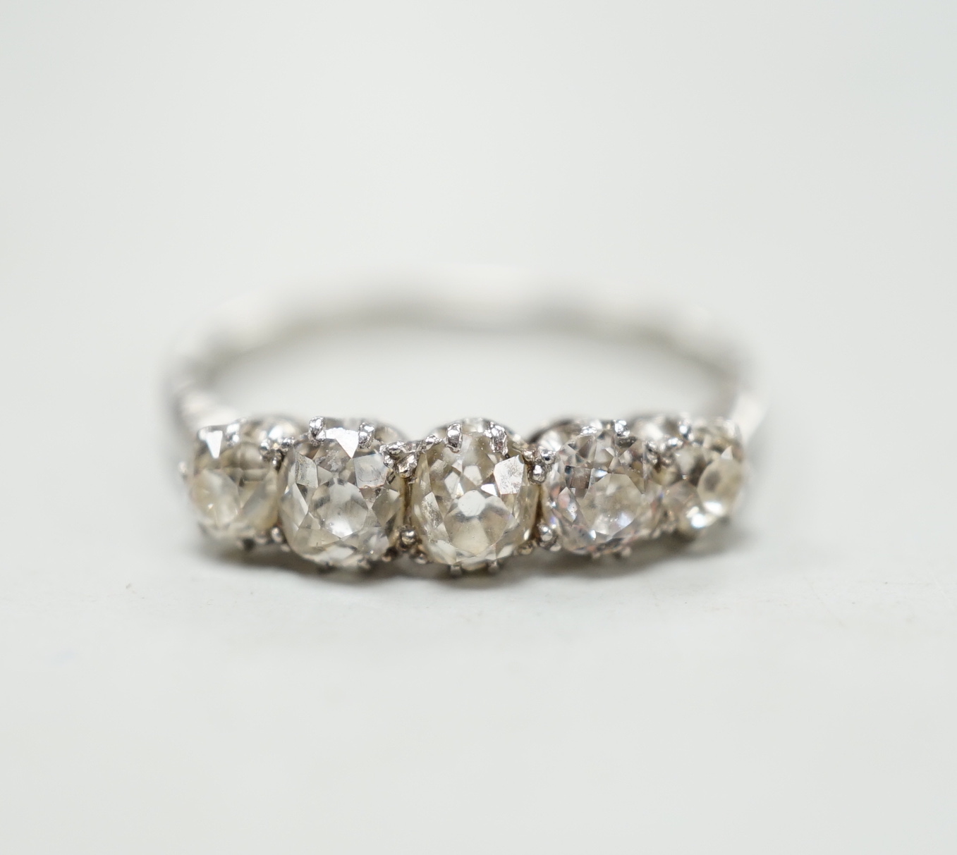 A 1940's white metal and graduated five stone diamond set half hoop ring, size M/N, gross weight 2.8 grams.